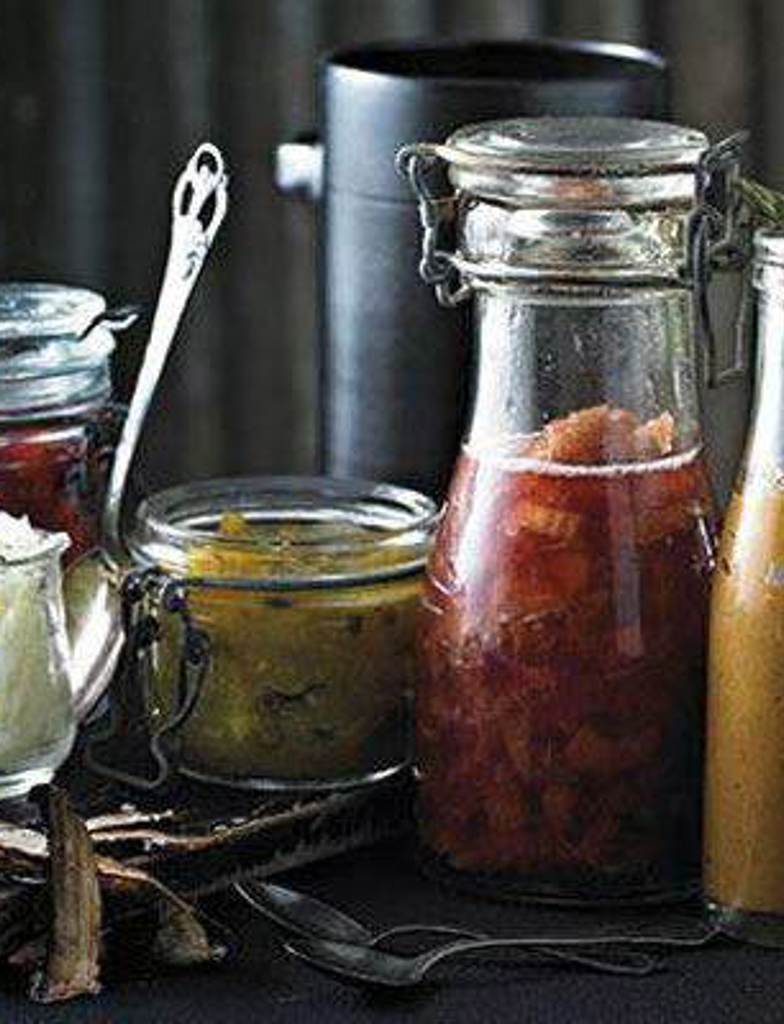 jars and containers filled with various gourmet hot dog toppings